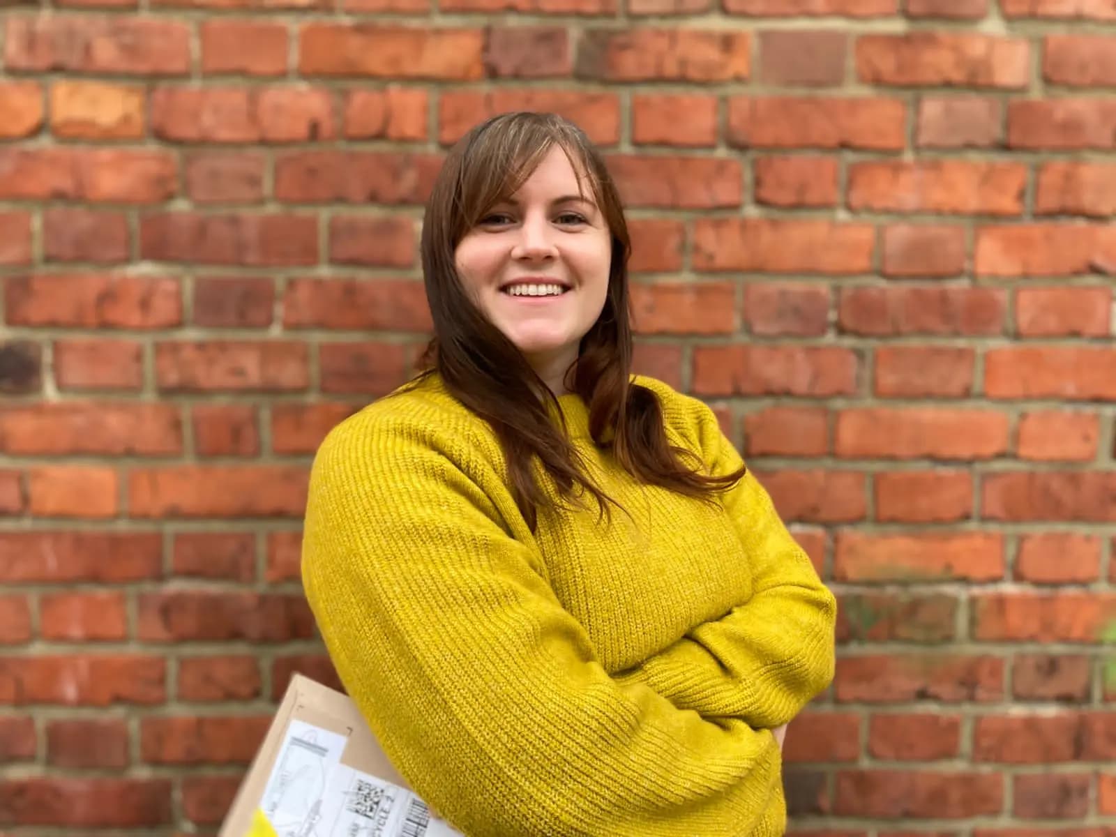 Lydia smiling in front of a brick wall